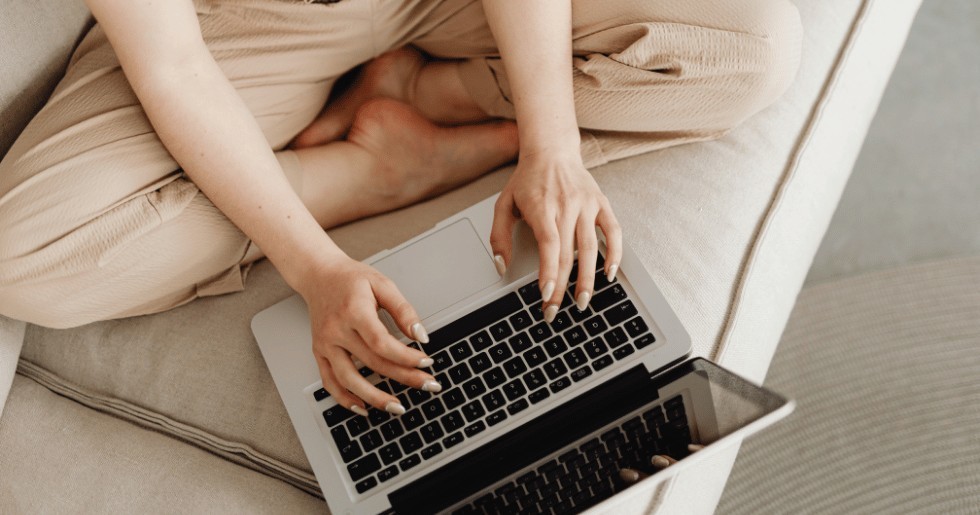Woman sitting cross-legged on a couch using a laptop for online therapy in Nevada